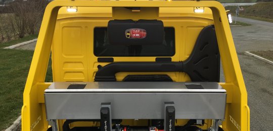 Un coffre à outils en inox avec ouverture par le dessus sur toute la largeur positionné sur la traverse du roll-bar