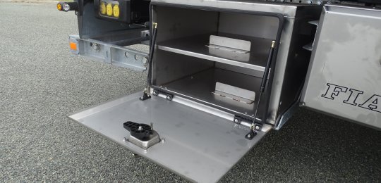 A closed stainless steel storage box with a fixed shelf for two wheel dollies type "GO-JACK 5000" (without dollies)
